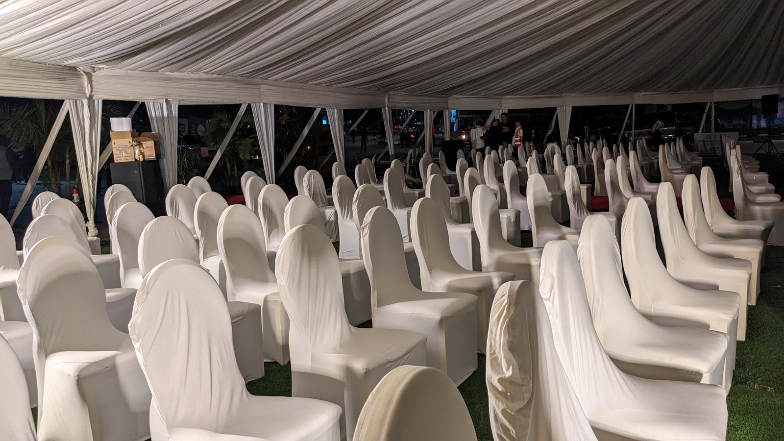 Rows of white covered chairs inside draped tent for ceremony seating